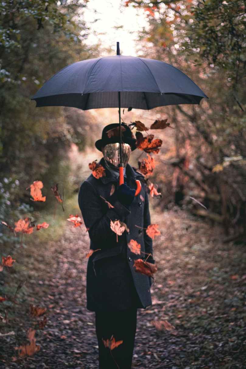 person wearing black topcoat holding black umbrella
