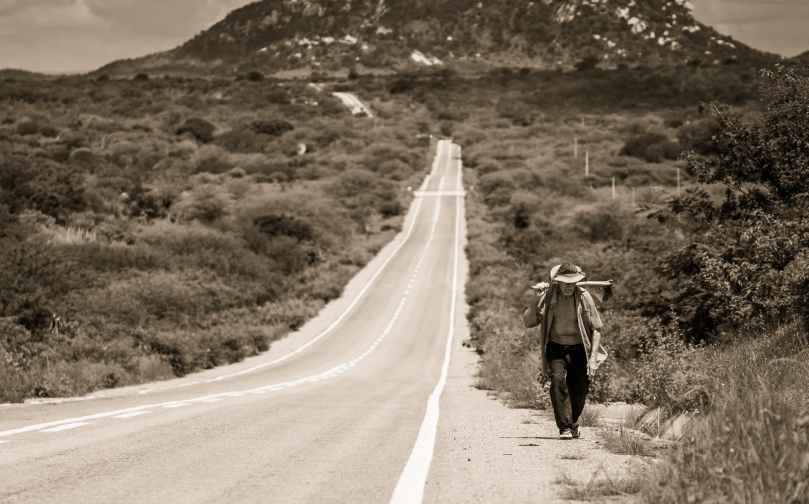 grayscale photo of man walking on road